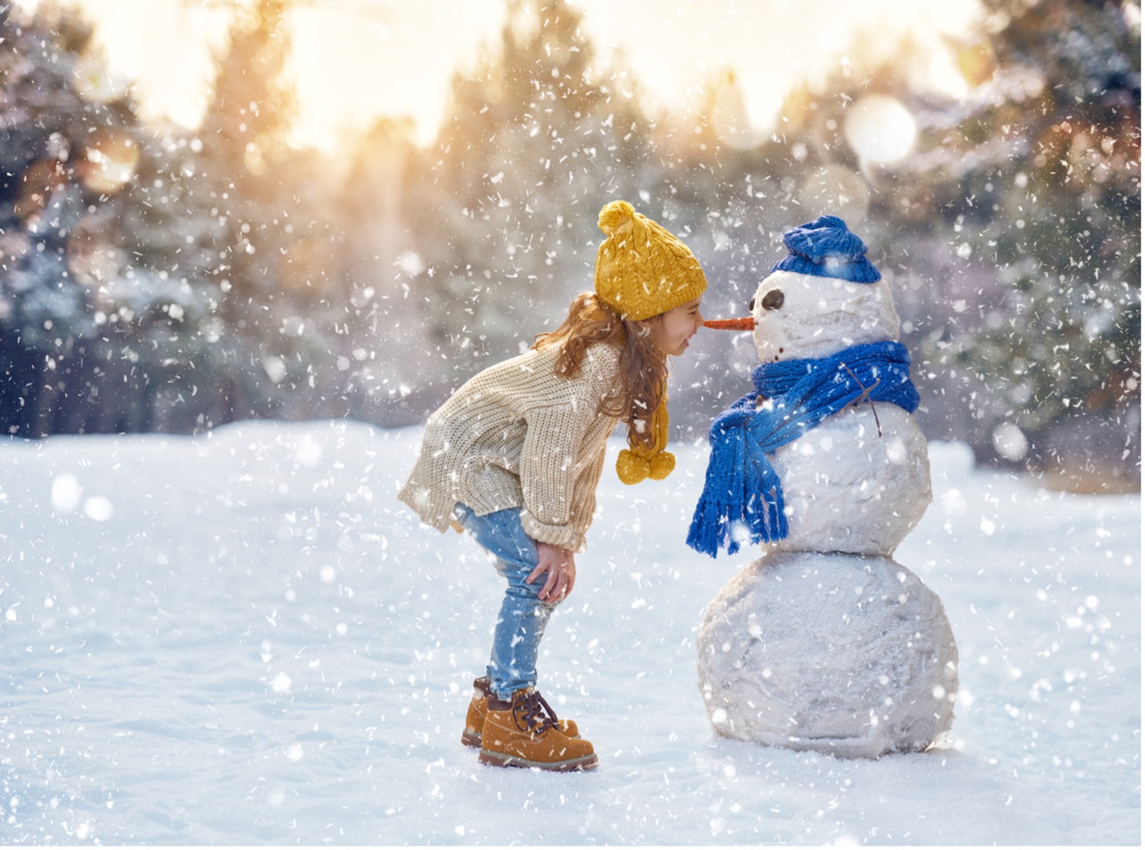 a child playing in the snow with a snowman