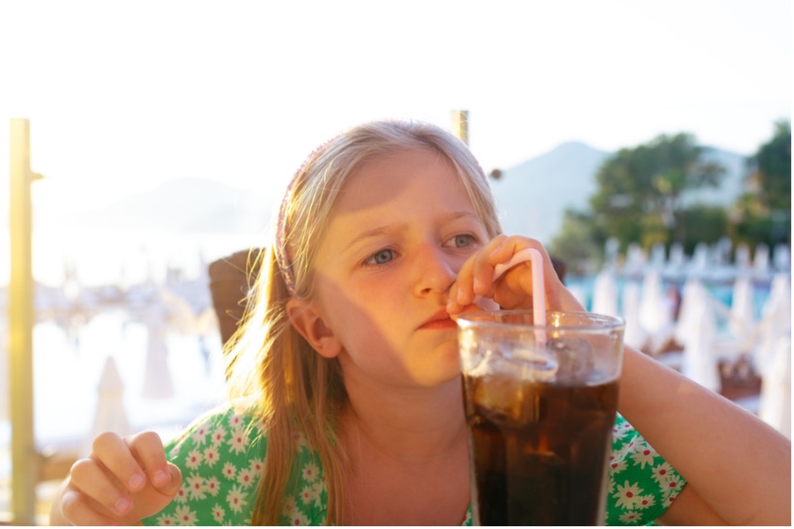 A child drinking cola soda from a glass