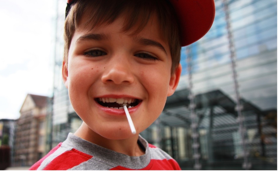 A child with a sugary snack lollipop in his mouth