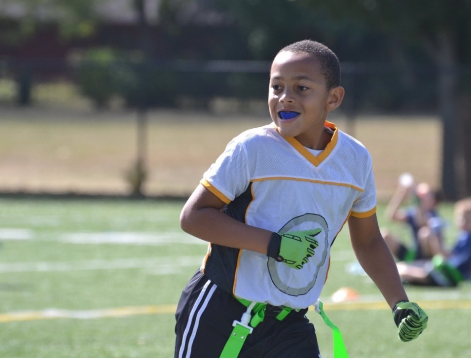A young person playing on a sports field with mouthguard in place