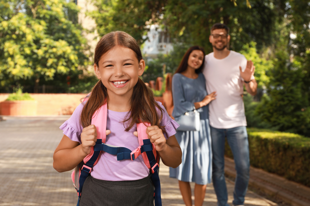 Parents waving goodbye to their daughter before school outdoors, 10 Back-to-School Dental Tips