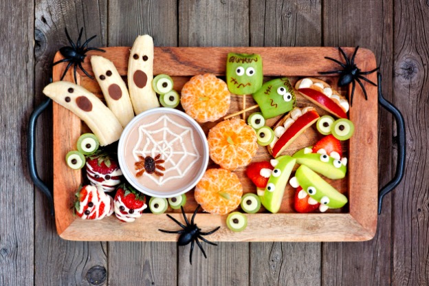A tray of healthy food and fruits in the shape of Halloween objects and monsters, spiders