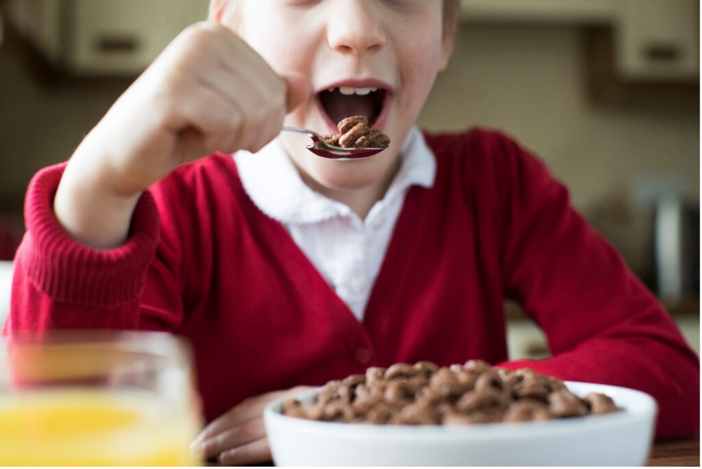 A child eating a sugary cereal with a spoon, how sugar affects children's teeth